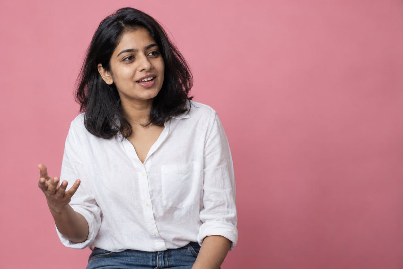 Example customer, a woman in a white shirt against a rose backdrop, mid-sentence.